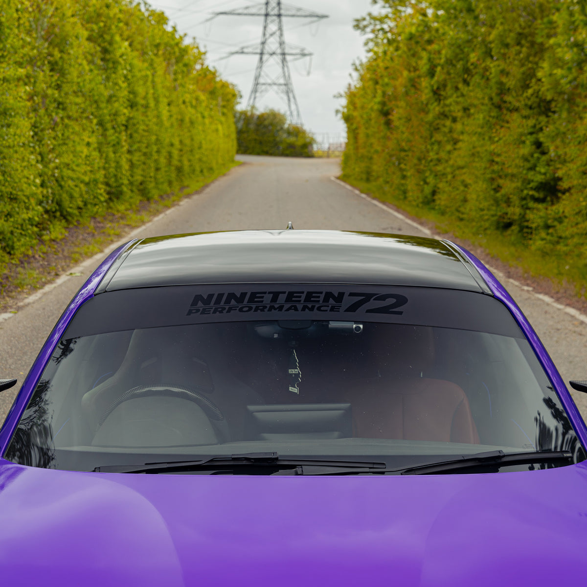 Nineteen72 Performance matte sunstrip with gloss black logo on a car, showcasing sleek automotive sunstrip design.