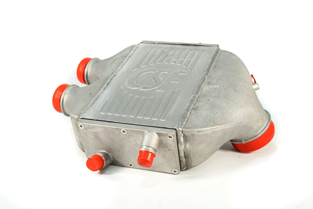 CSF Race F8X M4 top mount intercooler in raw finish, showcasing sleek metal construction and mounting features for high-performance cooling.