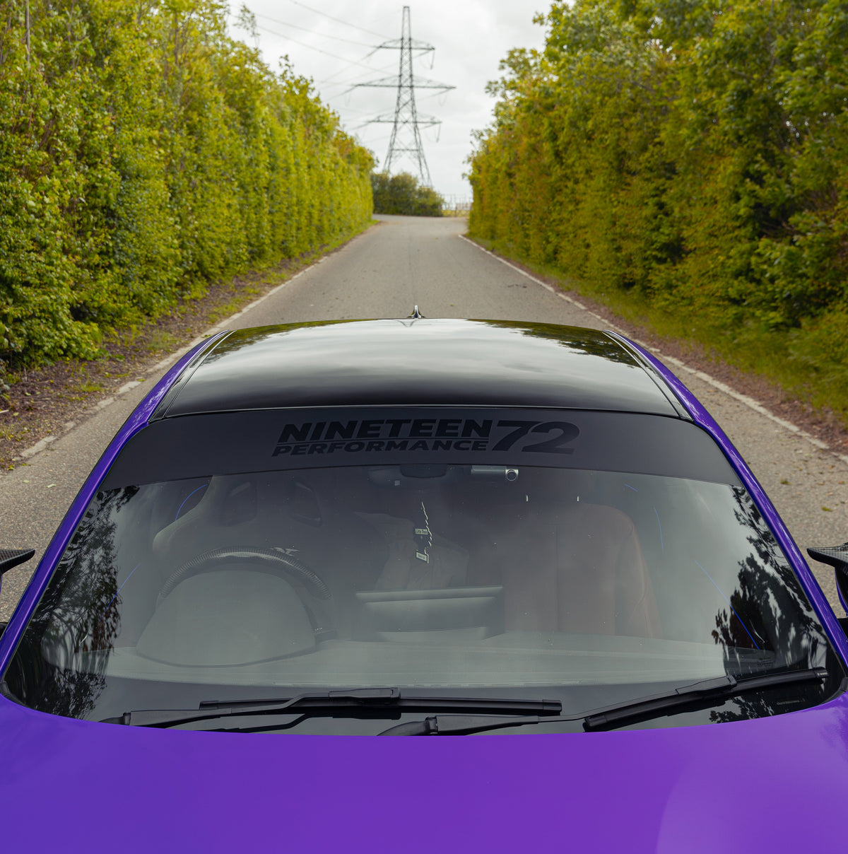 Nineteen72 Performance matte sunstrip with gloss black logo on a vehicle window for sporty style and sun protection.