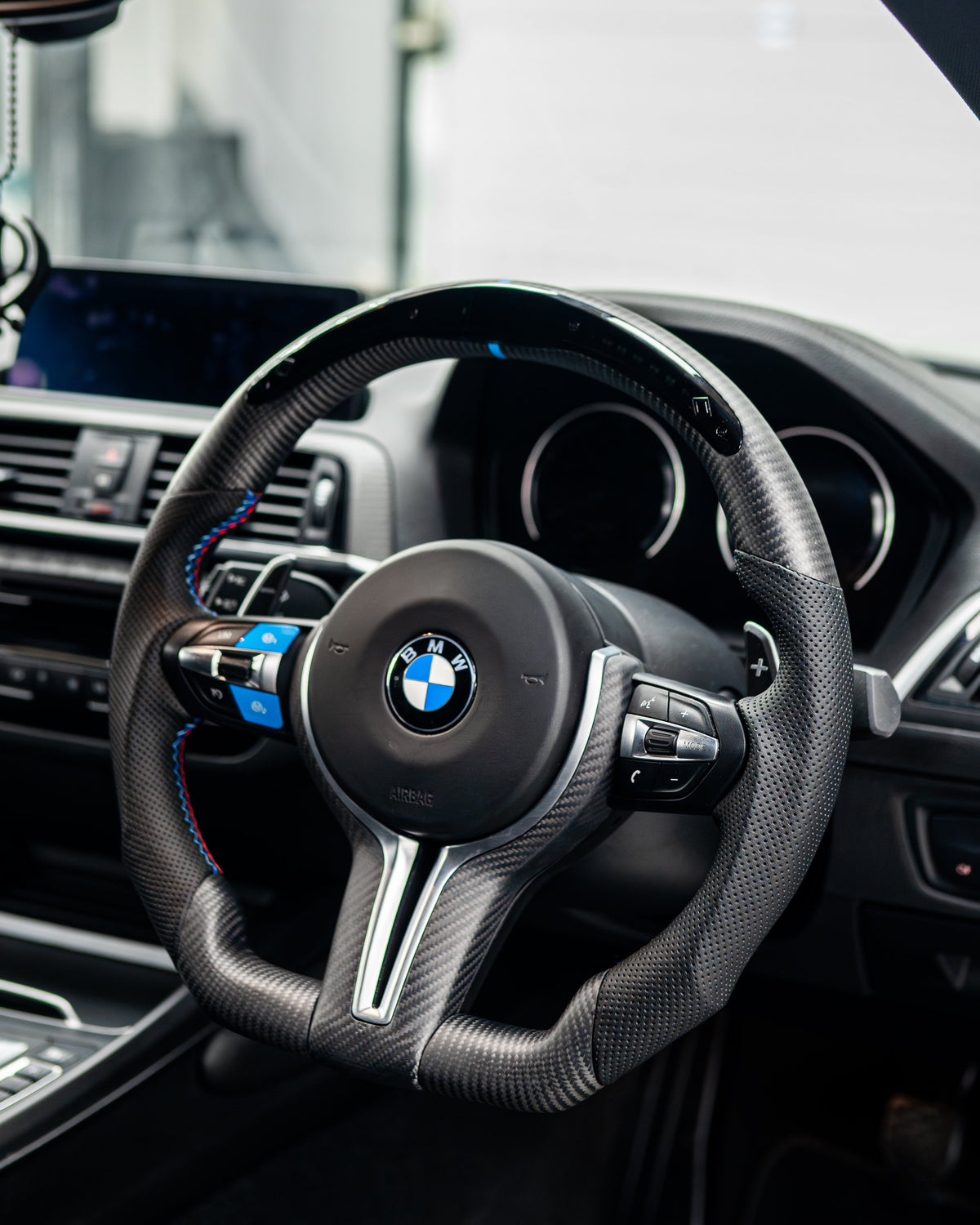 BMW Fxx M series matte carbon fibre steering wheel trim accessory by CT Carbon, showcasing sleek, textured carbon fibre finish.