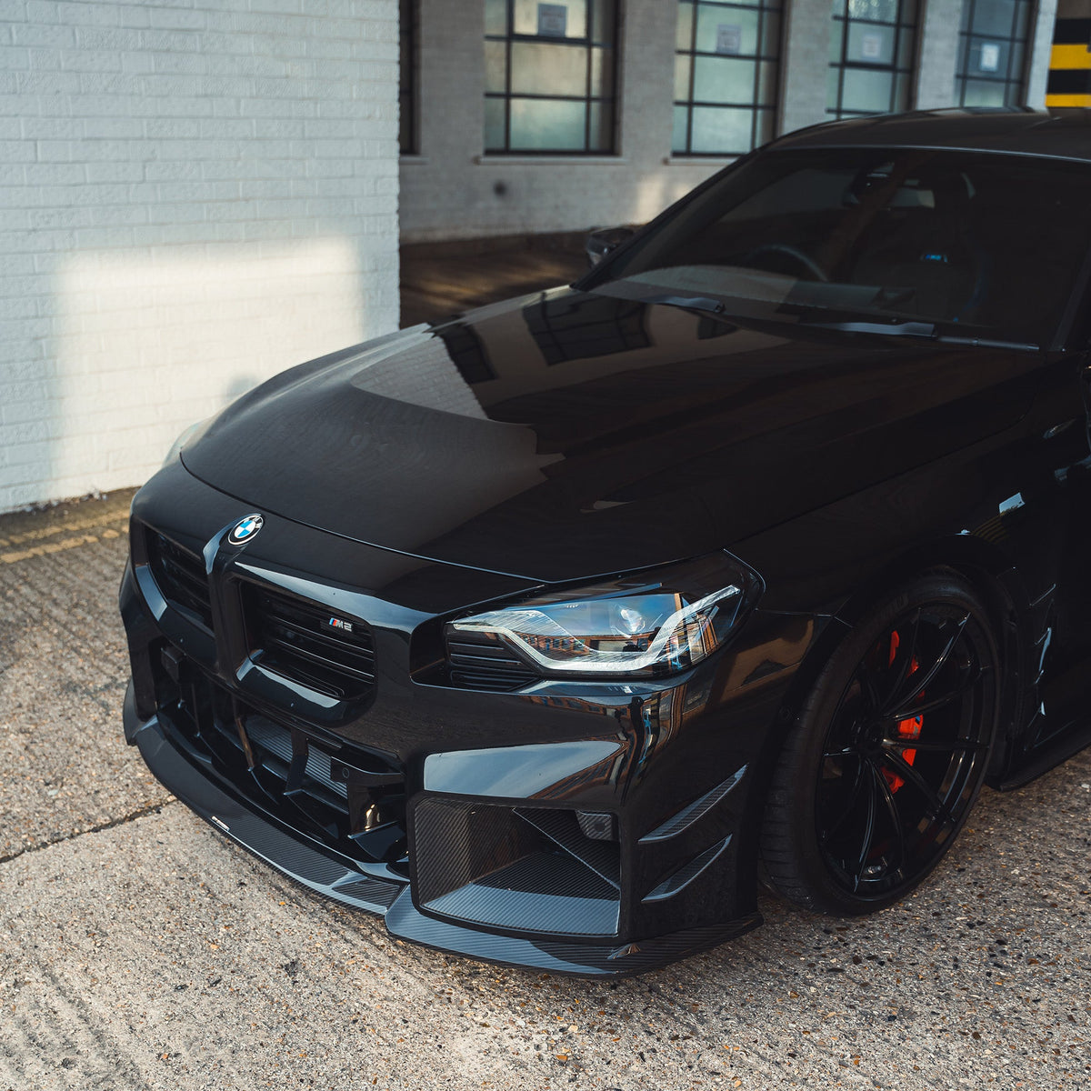 BMW G87 M2 carbon fibre front bumper canards by CT Carbon, close-up of lightweight aerodynamic accessories on the car's front.