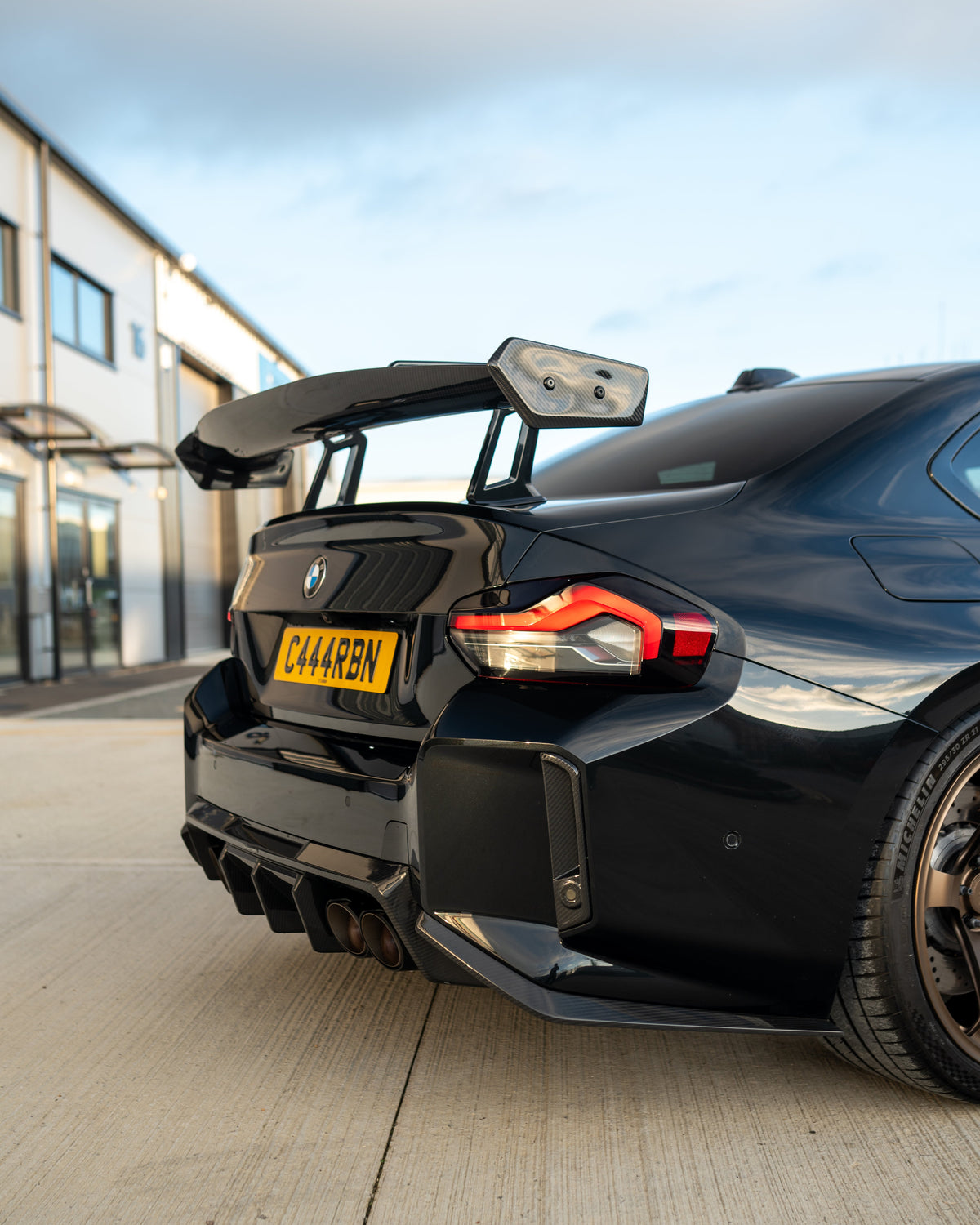 BMW G87 M2 and G42 2 Series carbon fibre swan neck wing spoiler by CT Design, shown on the sleek car in the image.