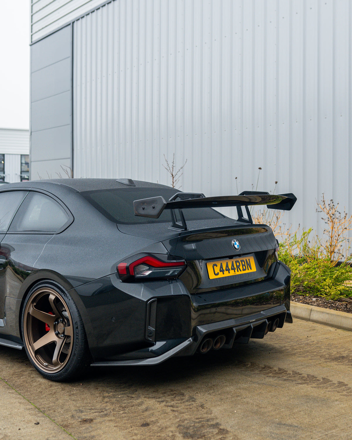 BMW G87 M2 and G42 2 Series carbon fibre swan neck wing spoiler by CT Design, shown on the car's rear for enhanced aerodynamics.