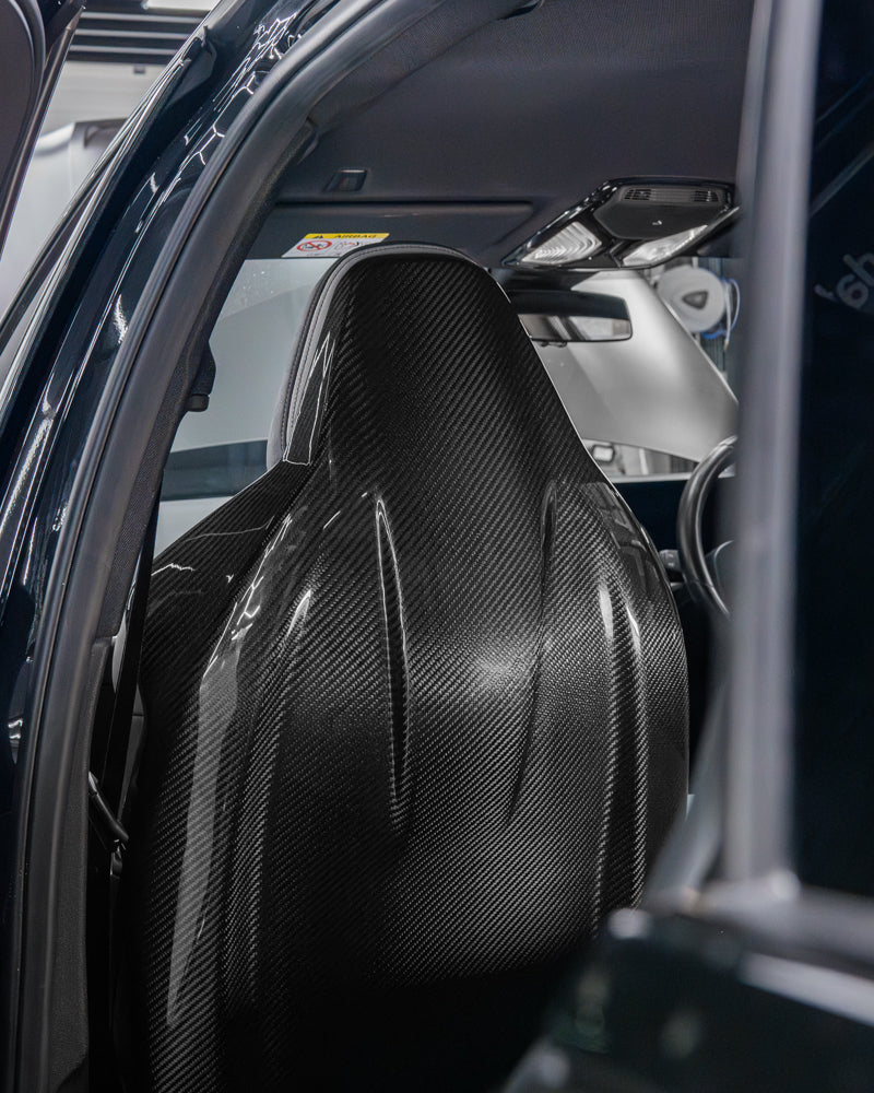 Carbon fiber seat backs for BMW GXX/F9X by CT Carbon, showcasing sleek, lightweight, textured carbon fiber material.