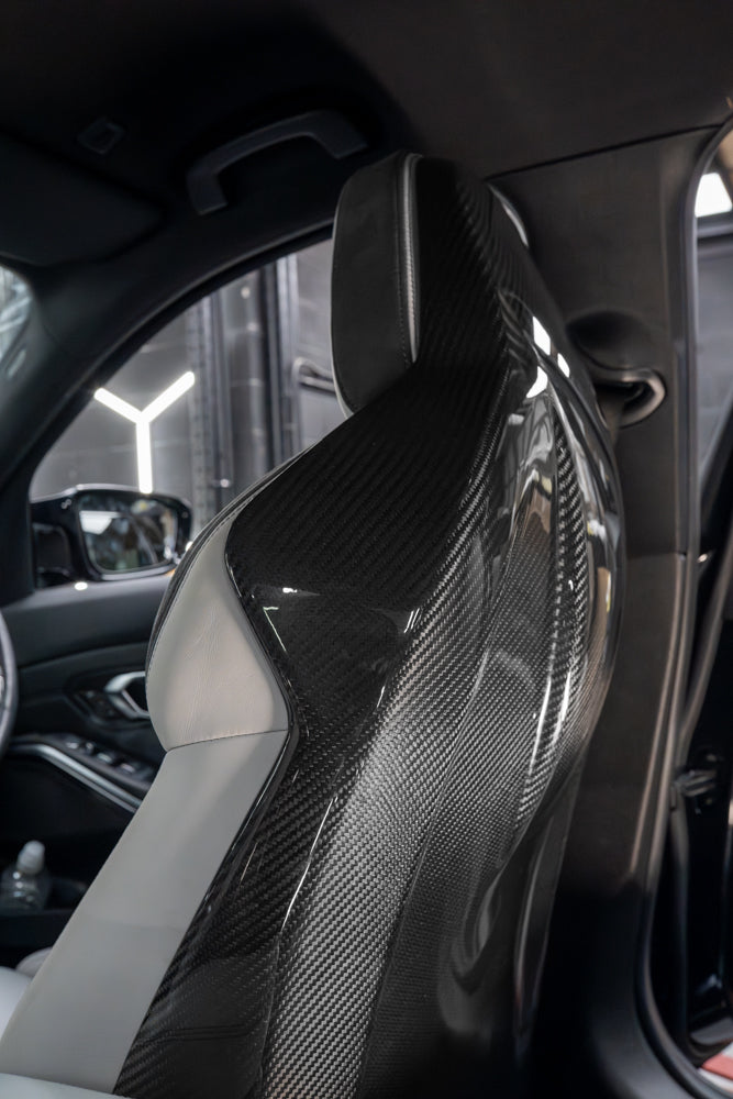 BMW GXX/F9X full carbon fibre seats backs by CT Carbon, showcasing sleek, lightweight carbon fiber material on car seat backs.