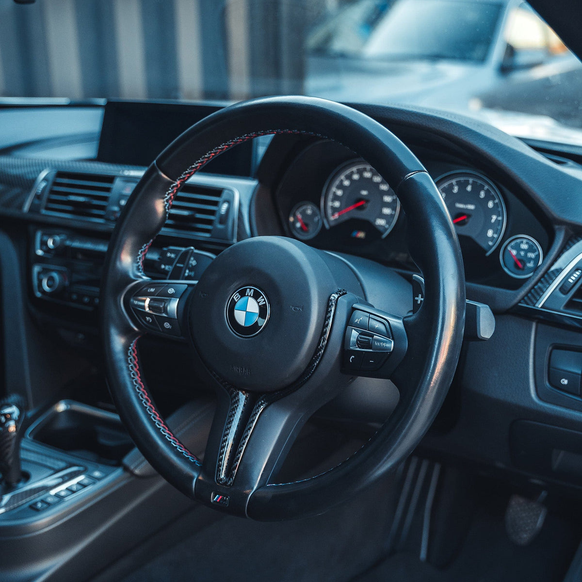 BMW M Fxx carbon fiber steering wheel trim accessory from CT Carbon, showcasing sleek black carbon fiber surface and detailed fitting area.