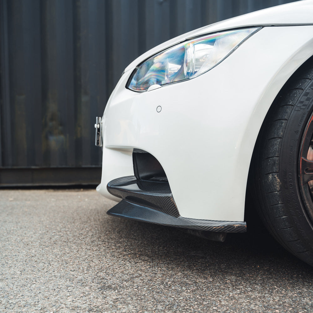 BMW M3 E92/E90 carbon front canard splitters by CT Carbon, showing their sleek, aerodynamic design on the car's front bumper.