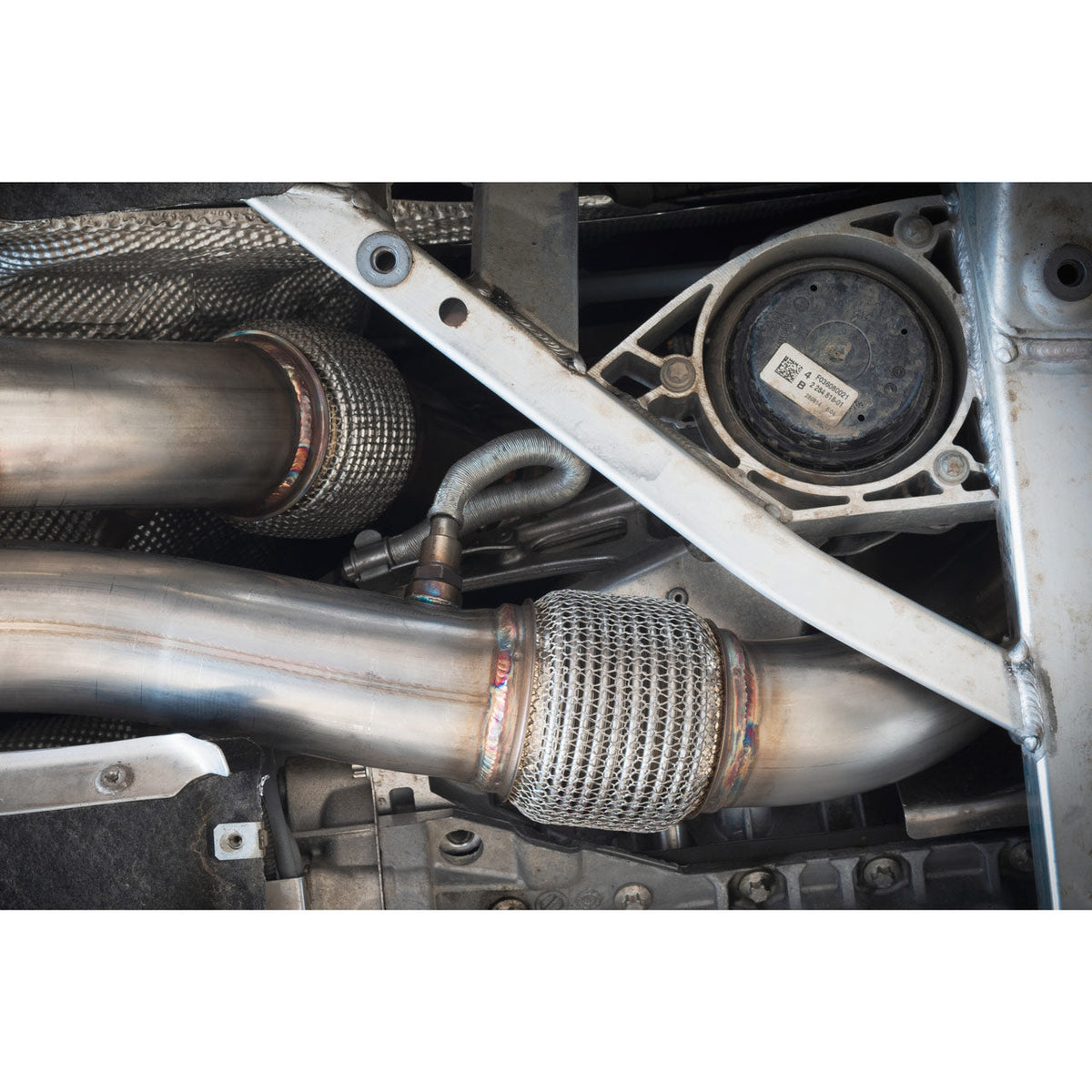 Cobra Sport BMW M4 F82 coupe 3-inch primary de-cat downpipe exhaust showing polished metal and connection points.