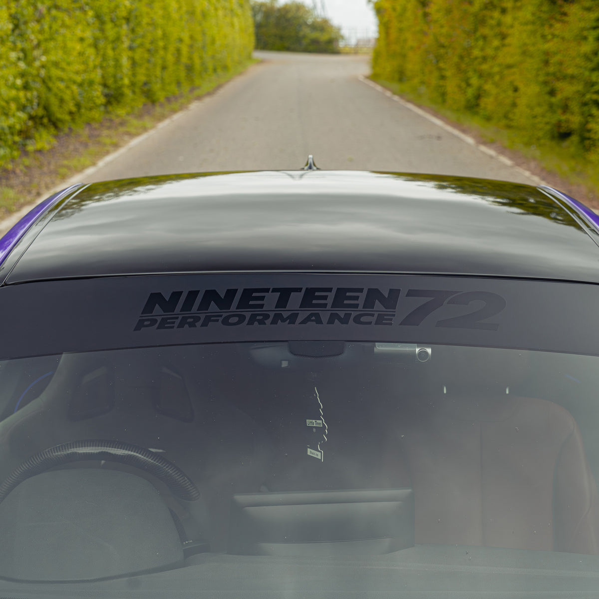 Nineteen72 Performance matte sunstrip with gloss black logo, designed for automotive use, shown on a vehicle.