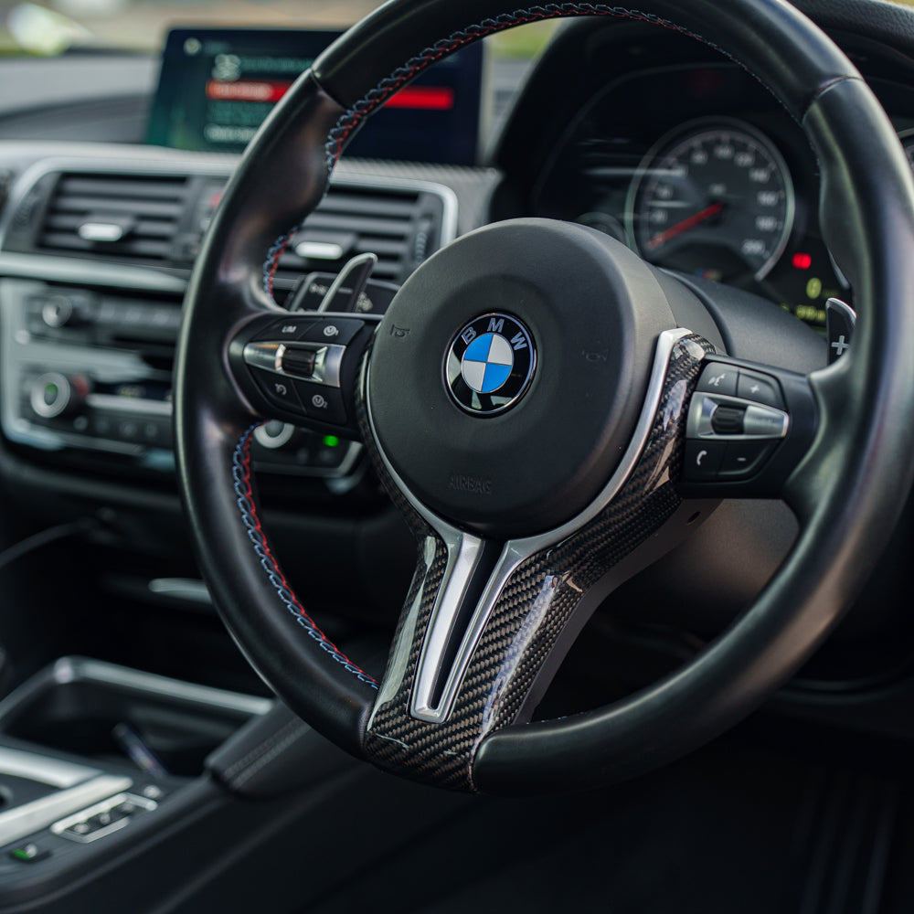 BMW Fxx M series carbon fiber steering wheel trim by CT Carbon, close-up of sleek, textured interior accessory.