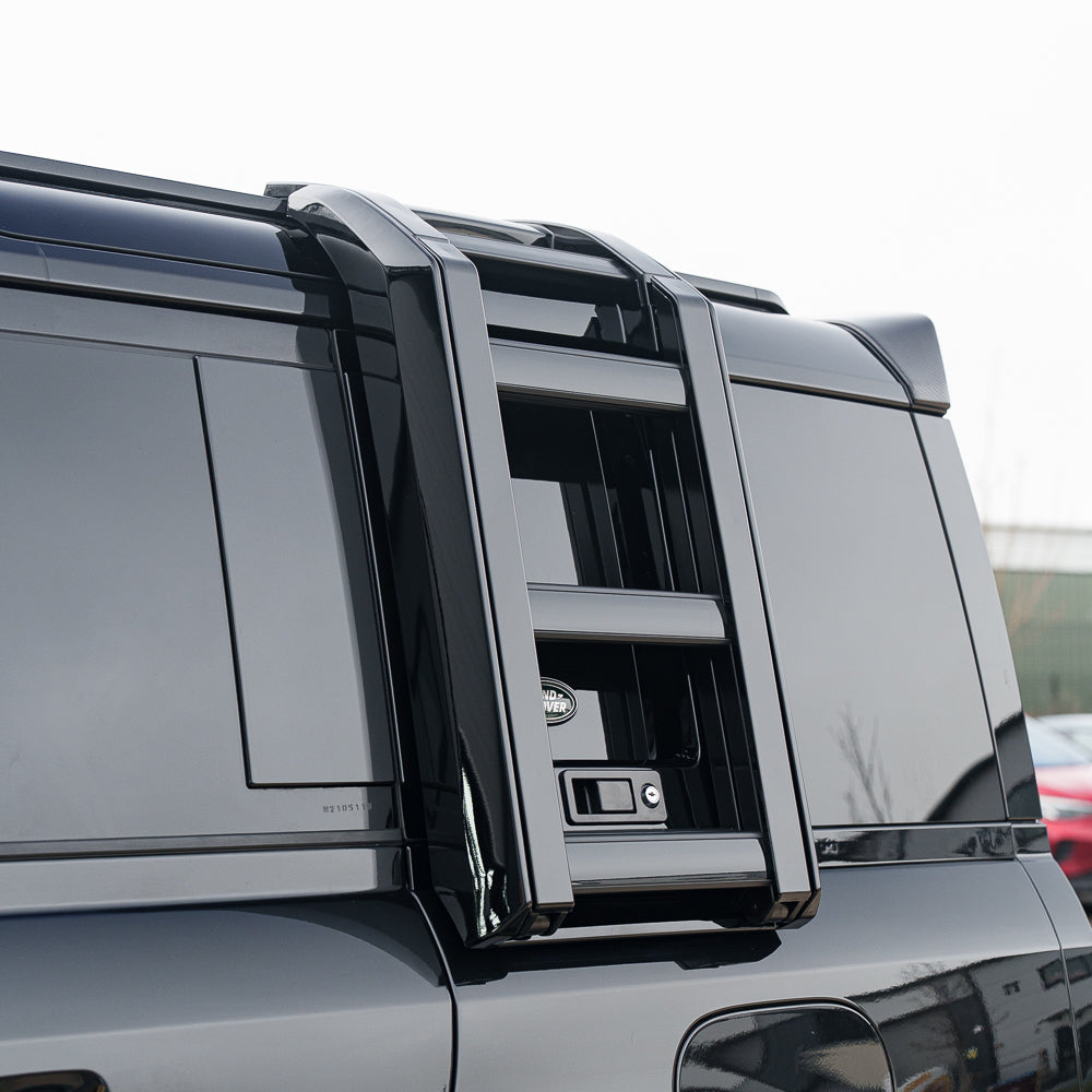 Gloss black ladder accessory for Land Rover Defender L663 110 and 90, made by CT Carbon, shown mounted on the vehicle.