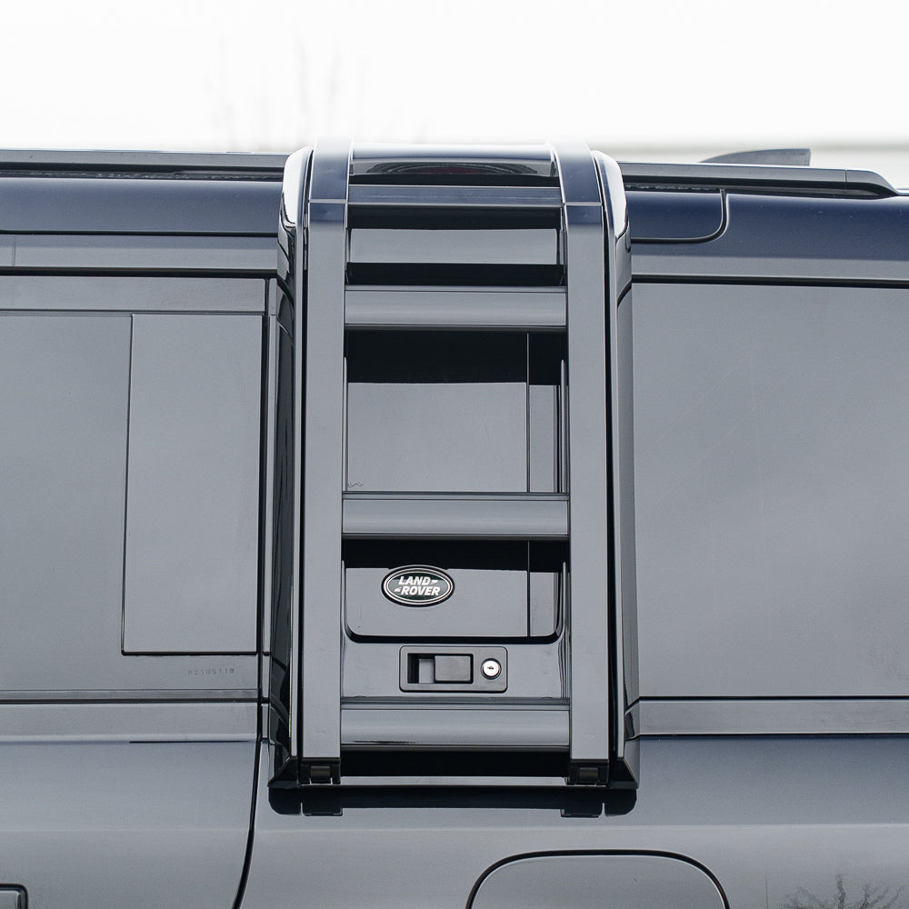 Gloss black ladder accessory for Land Rover Defender L663 110 and 90 by CT Carbon, mounted on the vehicle's rear side.