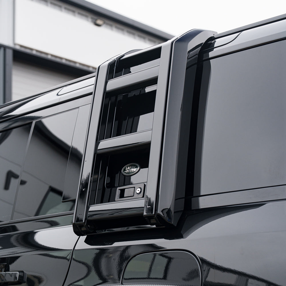 Gloss black ladder accessory for Land Rover Defender L663 110 and 90 by CT Carbon, mounted on the vehicle side.