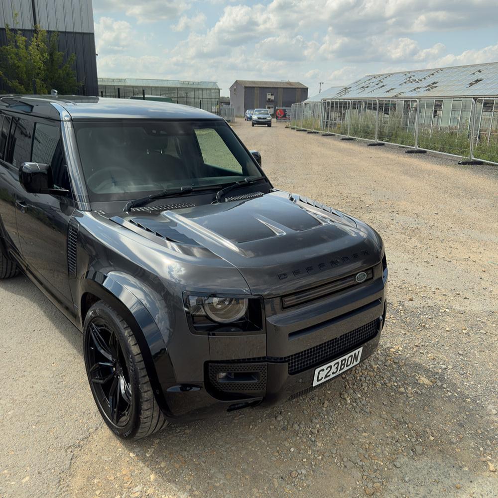 Carbon fiber bonnet for Land Rover Defender L663 SV style, featuring a sleek, lightweight design with textured carbon fiber surface.