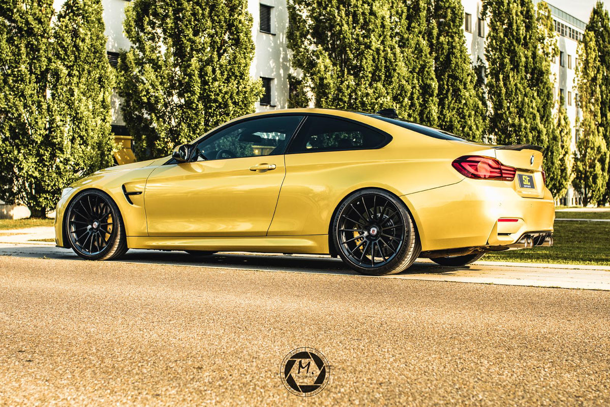 ST Suspension coilovers for BMW F80 M3 and F82 M4 with adjustable damping and top mounts, shown on a gold BMW F82 M4 coupe.