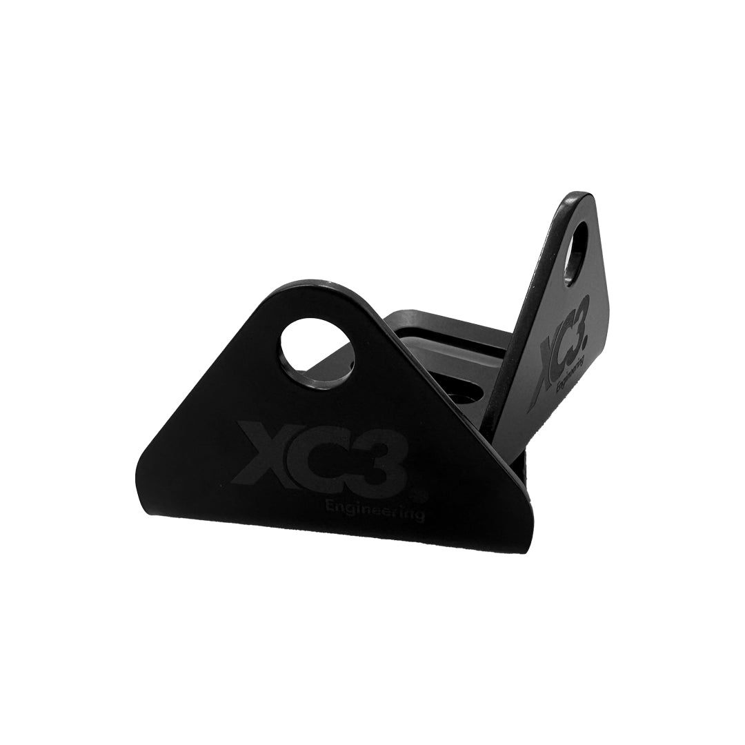 XC3 Engineering seat belt and harness mounting bracket for vehicle interior and safety, shown in black metal with mounting holes.