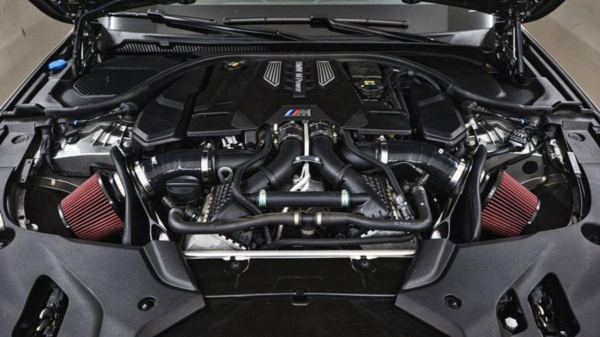 MST Performance induction kit installed in a BMW M5 or M8 Competition, showing the air intake components and branding.
