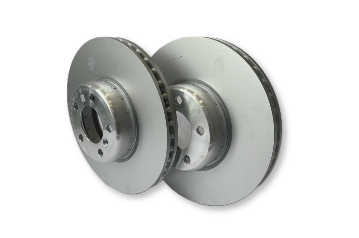 Genuine BMW front brake discs and pads for 1/2/3/4 Series, showing clean metal brake discs and brake pad set in natural lighting.