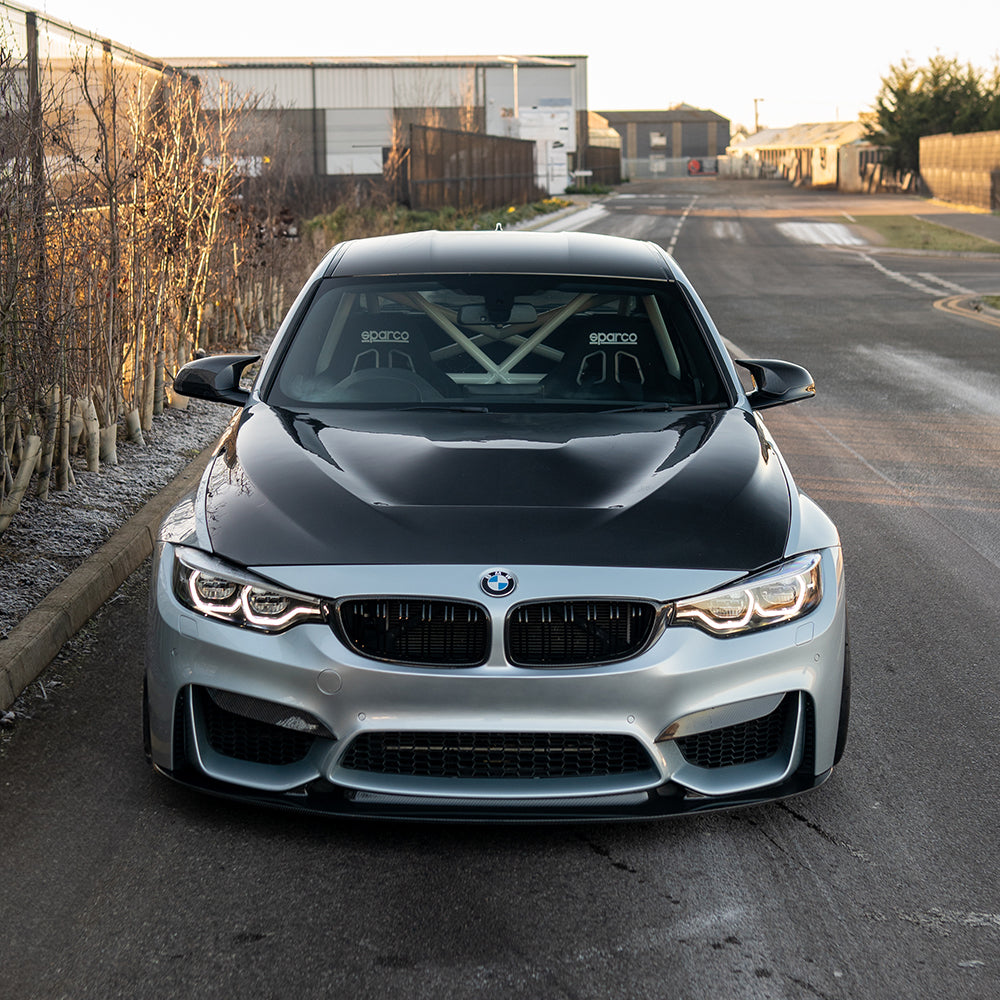 BMW M3 M4 F80 F82 F83 carbon fiber splitter by CT Carbon, shown on a sunset scene highlighting the sleek splitter design.