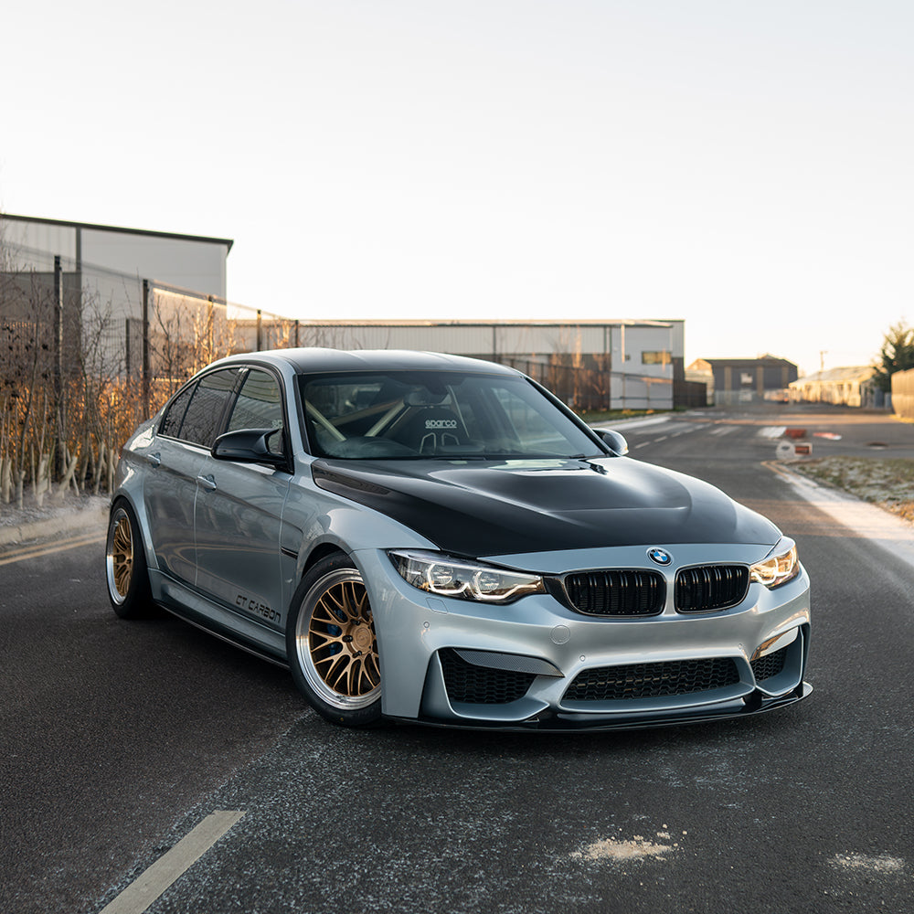 BMW M3 M4 F80 F82 F83 carbon fibre splitter by CT Carbon, showing the sleek V9 design on a sunset-lit vehicle.
