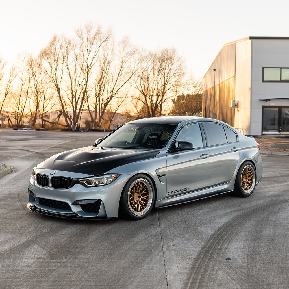 BMW M3 M4 F80 F82 F83 carbon fibre splitter by CT Carbon installed on a sunset-lit car, showcasing its aerodynamic design.