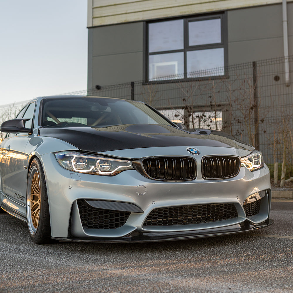 BMW M3 M4 F80 F82 F83 carbon fiber splitter by CT Carbon, shown in sunset lighting, highlighting its aerodynamic design.