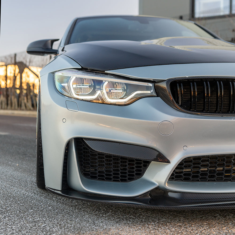 BMW M3 M4 F80 F82 F83 carbon fiber splitter V9 by CT Carbon, shown on a sunset background with detailed textured surface.