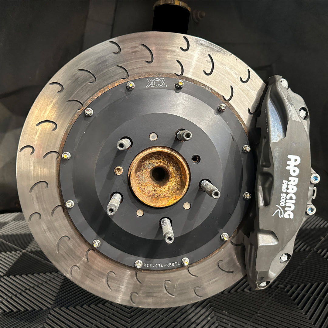 XC3 Engineering BMW M2 M3 M4 caliper carrier and BTCC rotor upgrade for AP Racing CP9660 brakes, installed on a car.