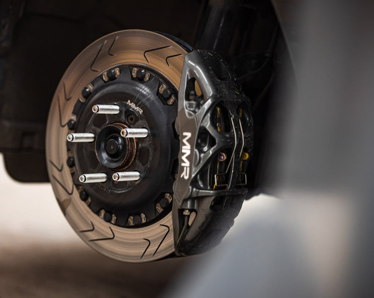 MMX Performance BMW MINI wheel stud and nut conversion kit with six studs and nuts, installed on a vehicle wheel.