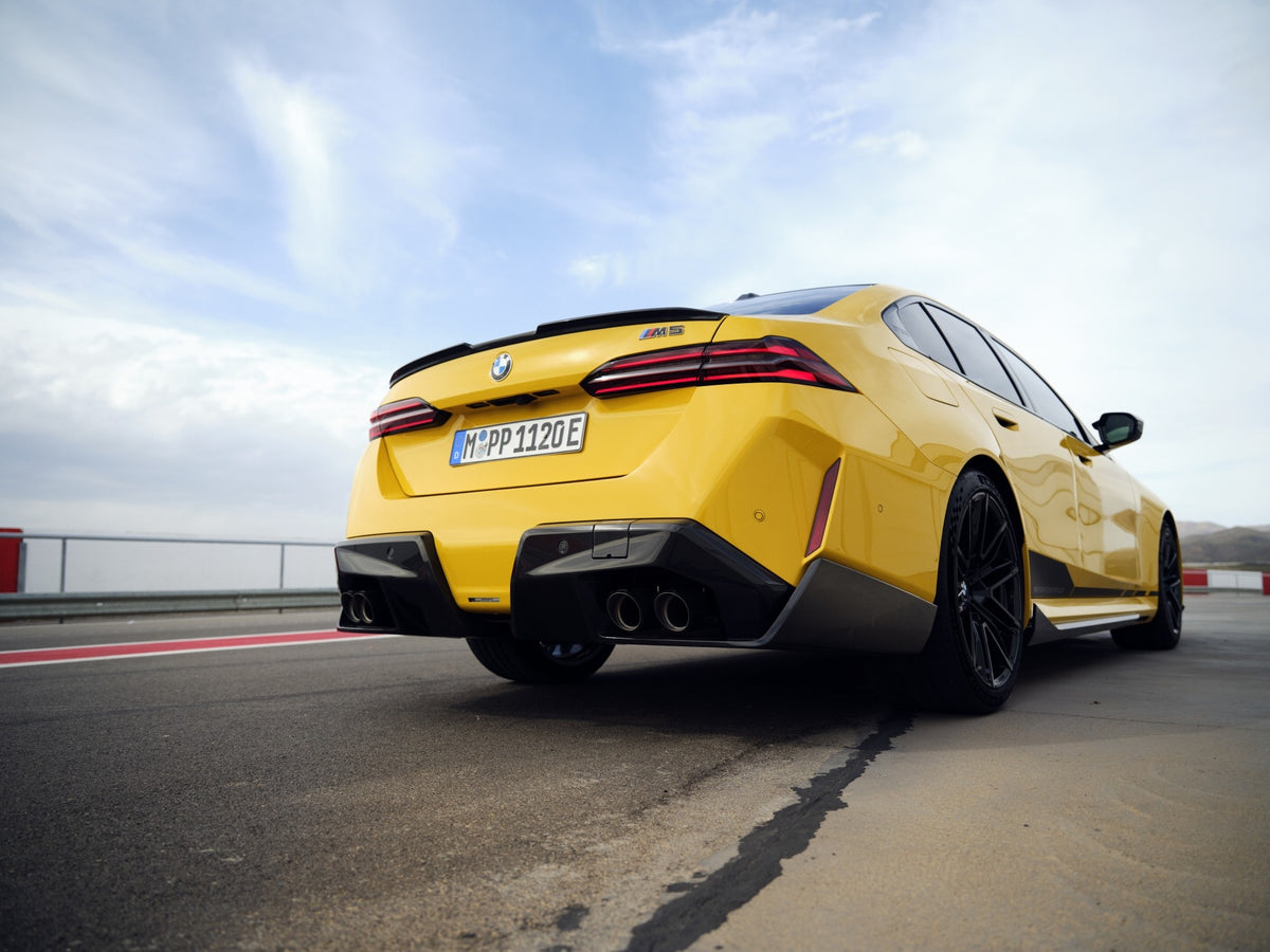 Genuine BMW M Performance G90 G99 M5 carbon rear diffuser kit installed on a sports sedan, showcasing its aerodynamic design.