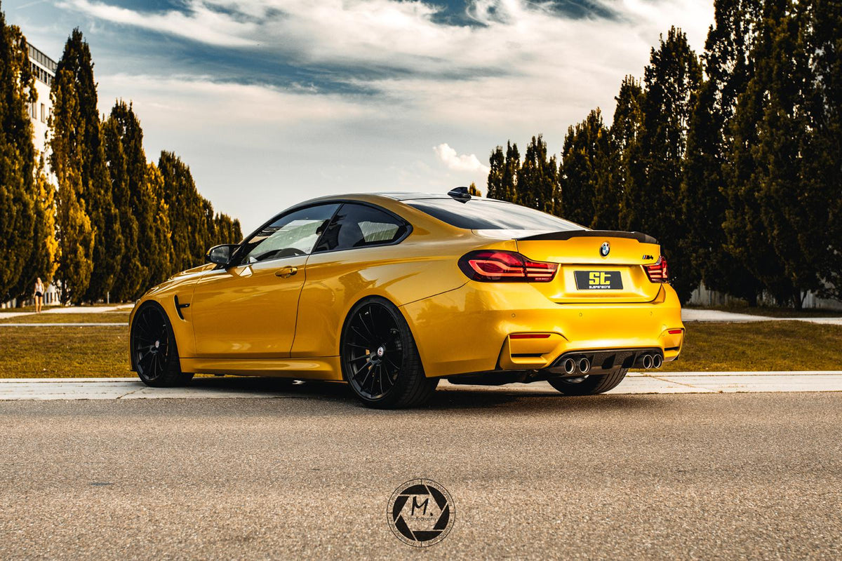 Gold ST Suspension coilovers installed on BMW F82 M4 coupe, featuring adjustable damping and top mounts for enhanced handling.