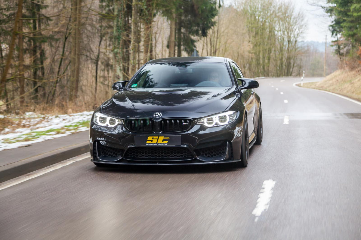 ST Suspension coilovers for BMW F80 M3 and F82 M4 coupe, showing adjustable damping and top mounts in the image.