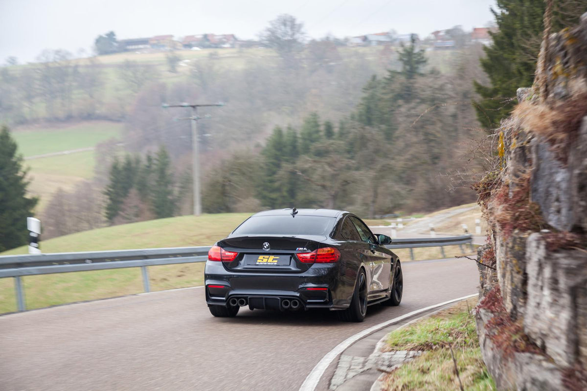 ST Suspension coilovers for BMW F80 M3 and F82 M4 coupe with adjustable damping and top mounts, shown on a black F82 M4 coupe.