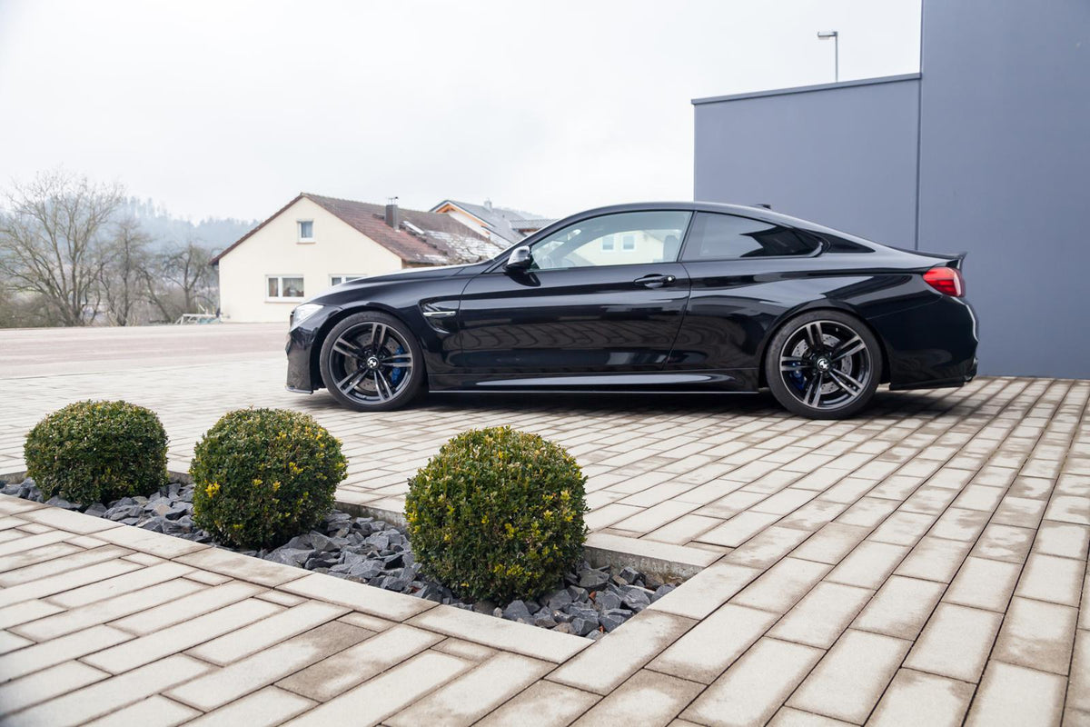 ST Suspension coilovers for BMW F80 M3, F82 M4 coupe with adjustable damping and top mounts, shown on a black BMW F82 M4 coupe.