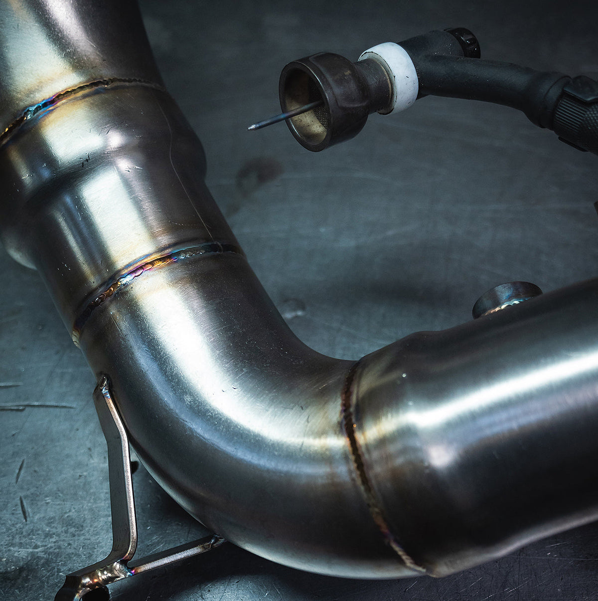 Cobra Sport VW Tiguan R front downpipe sports cat exhaust component, showcasing polished metal and automotive installation.