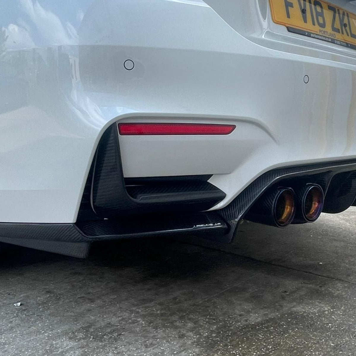 BMW M3 M4 F80 F82 F83 carbon fibre rear bumper canards by CT Carbon, showing aerodynamic accessories on the vehicle's rear.