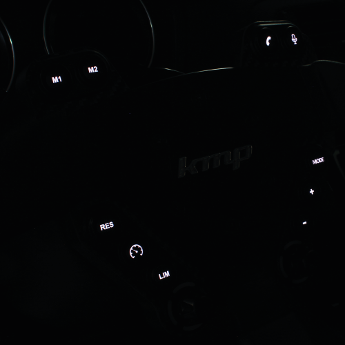 KMP Drivetrain Clubsport BMW FXX steering wheel with illuminated details, black and silver finish, showing close-up of textured grip and controls.